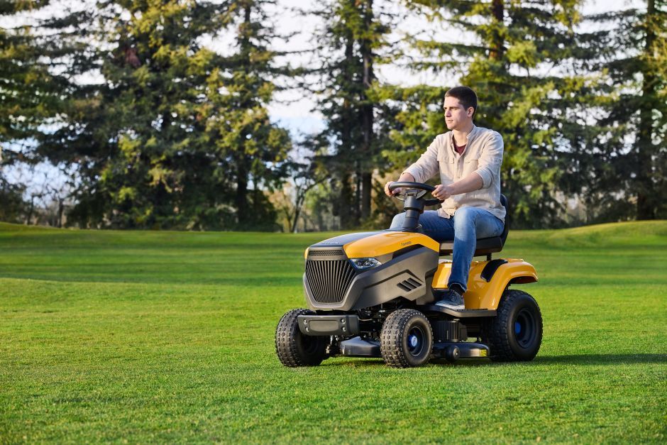 A Man Is Riding a Lawn Mower on A Lush Green Field — Stihl Shop Grafton in Yamba, NSW
