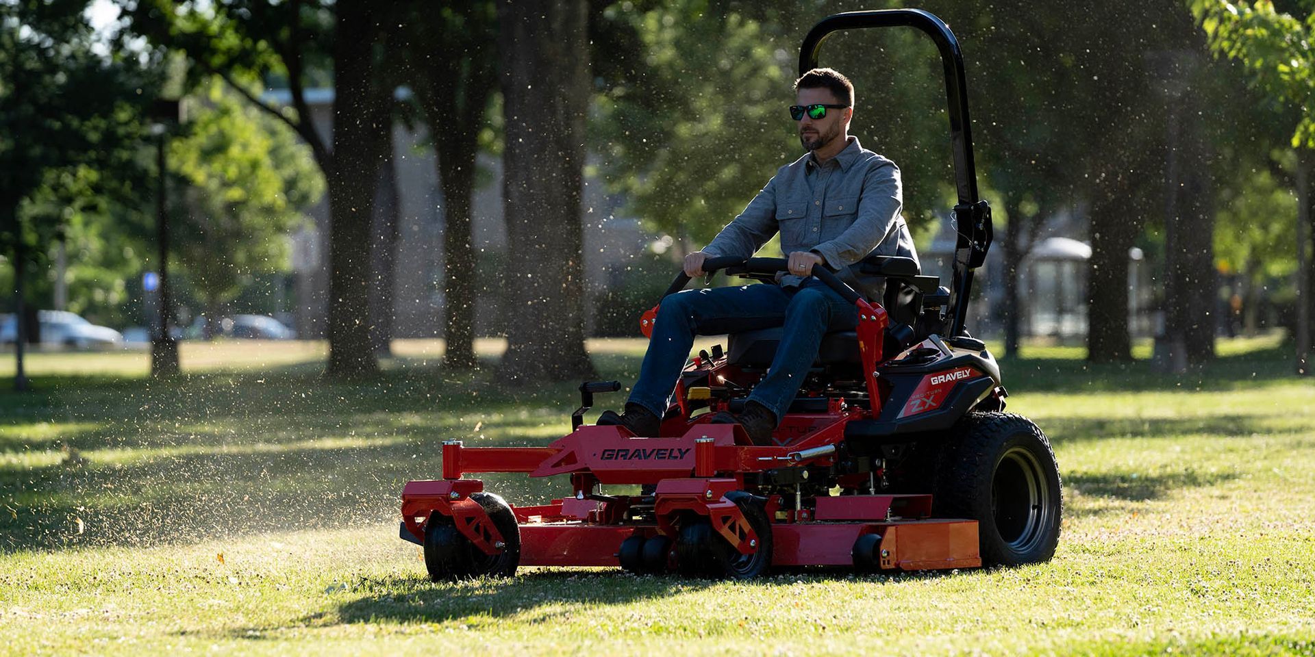 A Man Is Riding a Lawn Mower in A Park — Stihl Shop Grafton in Grafton, NSW