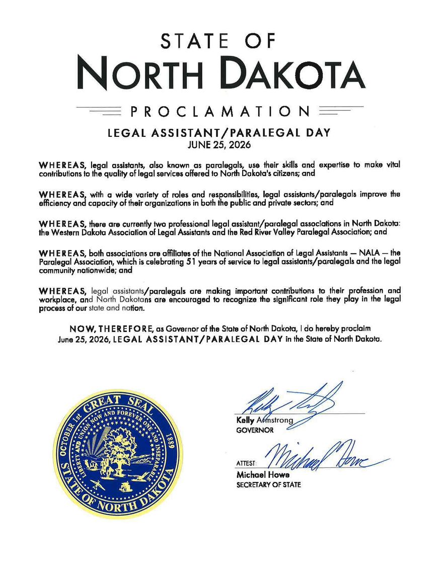 Seven people stand inside a building, holding a document near a state seal.