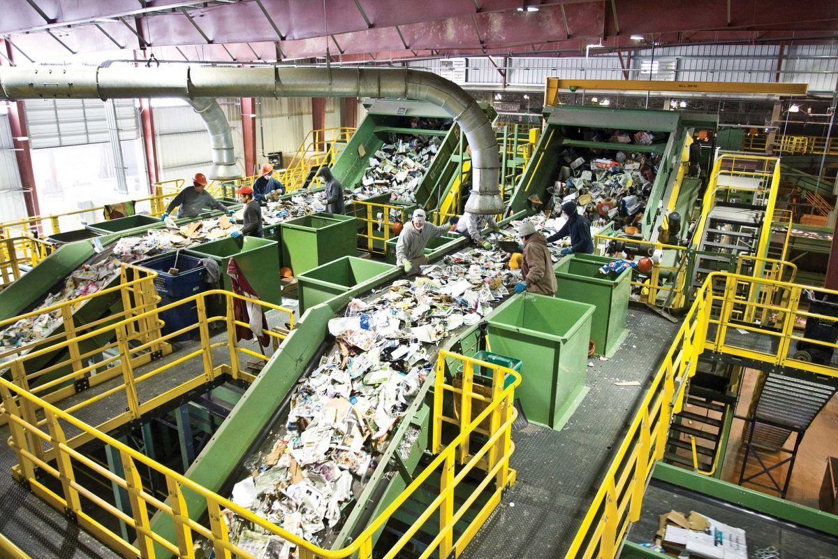 Picture of a recycling unit - with people around - multiple stages of waste processing