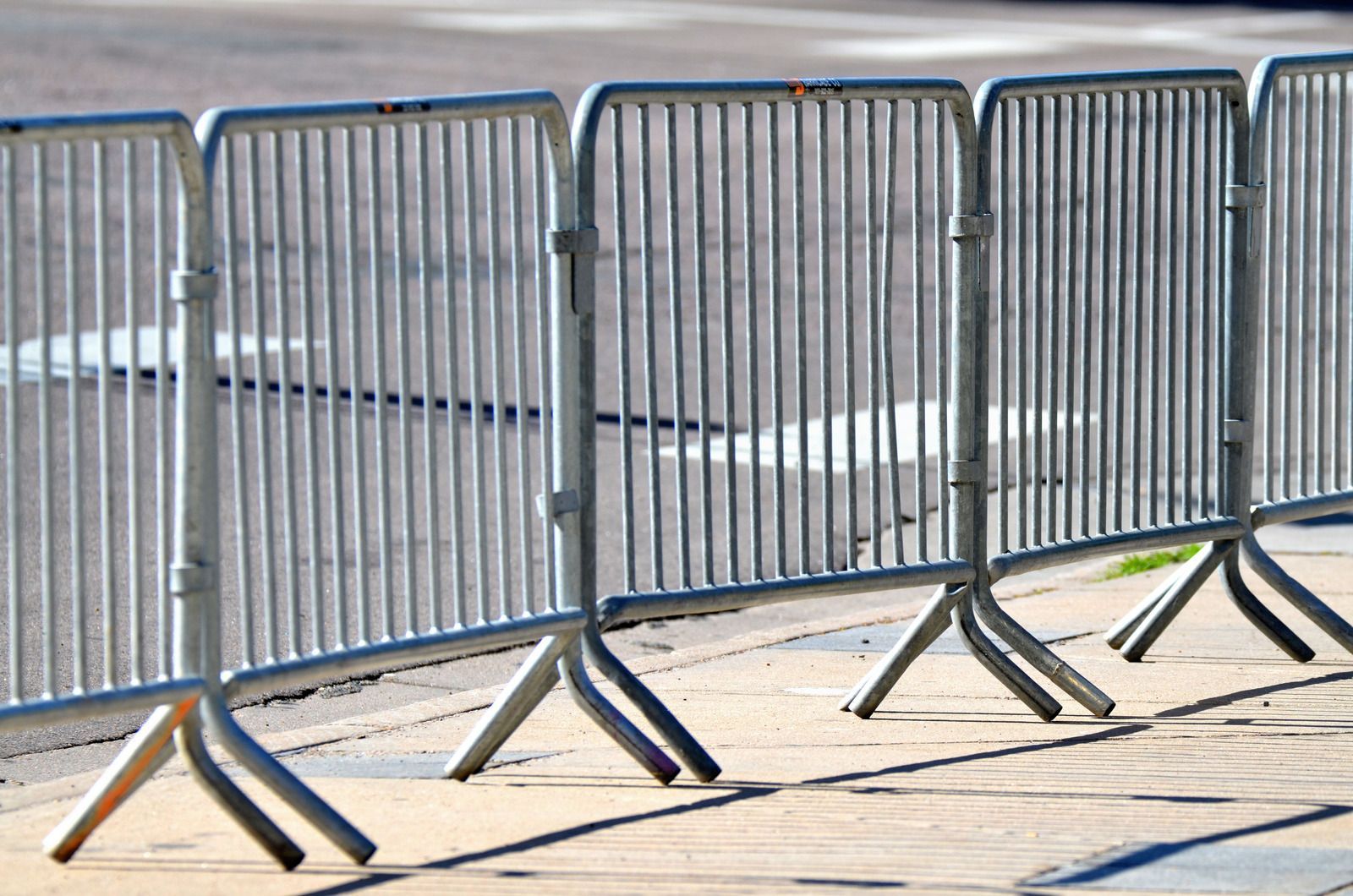 Metal crowd control barriers along a gravel path next to a road.