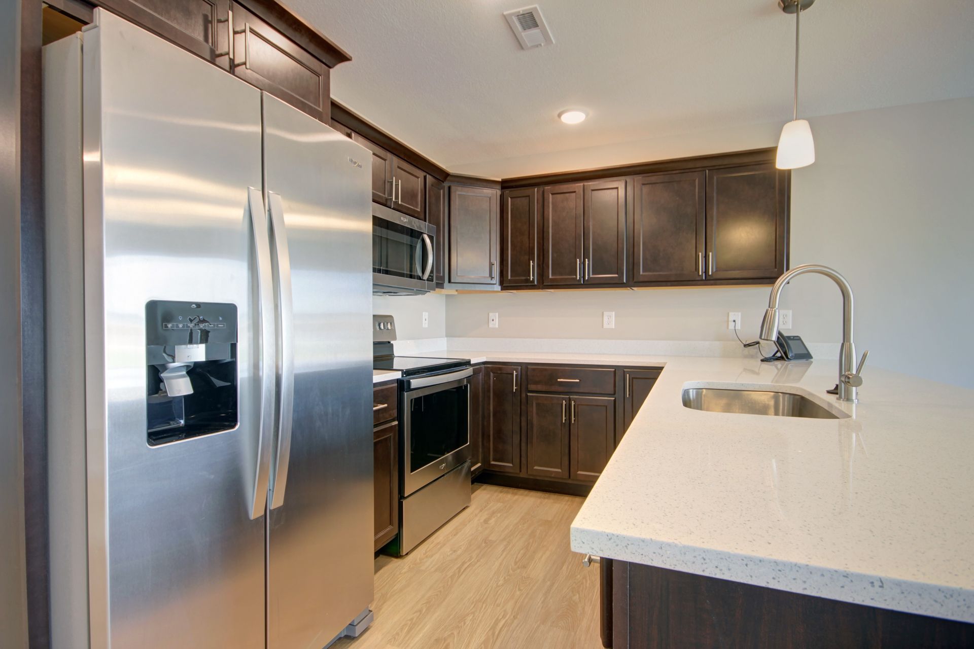 Modern kitchen with stainless steel refrigerator, dark cabinets, and light countertops