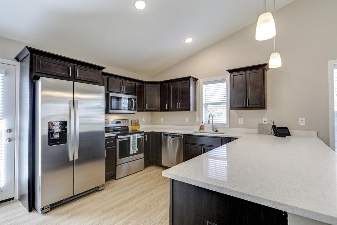 Modern kitchen with stainless steel appliances, dark cabinets, and a white island countertop
