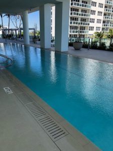 Covered outdoor infinity pool with blue water beside a modern condo building
