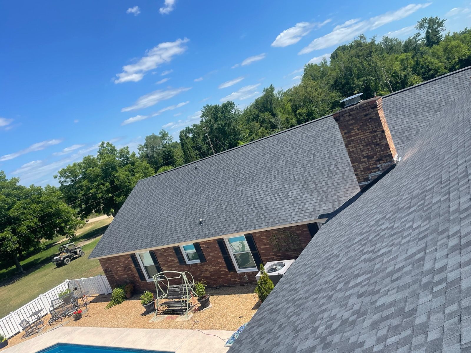 A house with a newly shingled roof, brick chimney, and a blue sky in the background.