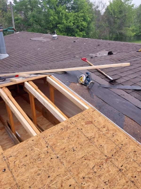 Roof with exposed wooden supports, new sheathing, and tools, in progress of repair, outdoors.