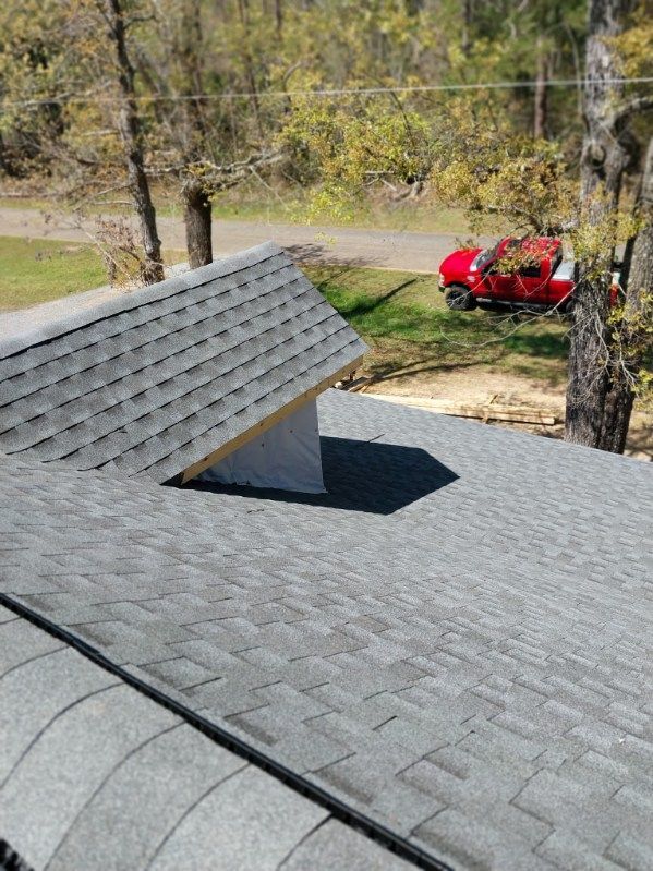 Gray shingled roof with a small, unfinished structure. Red truck visible in the background.