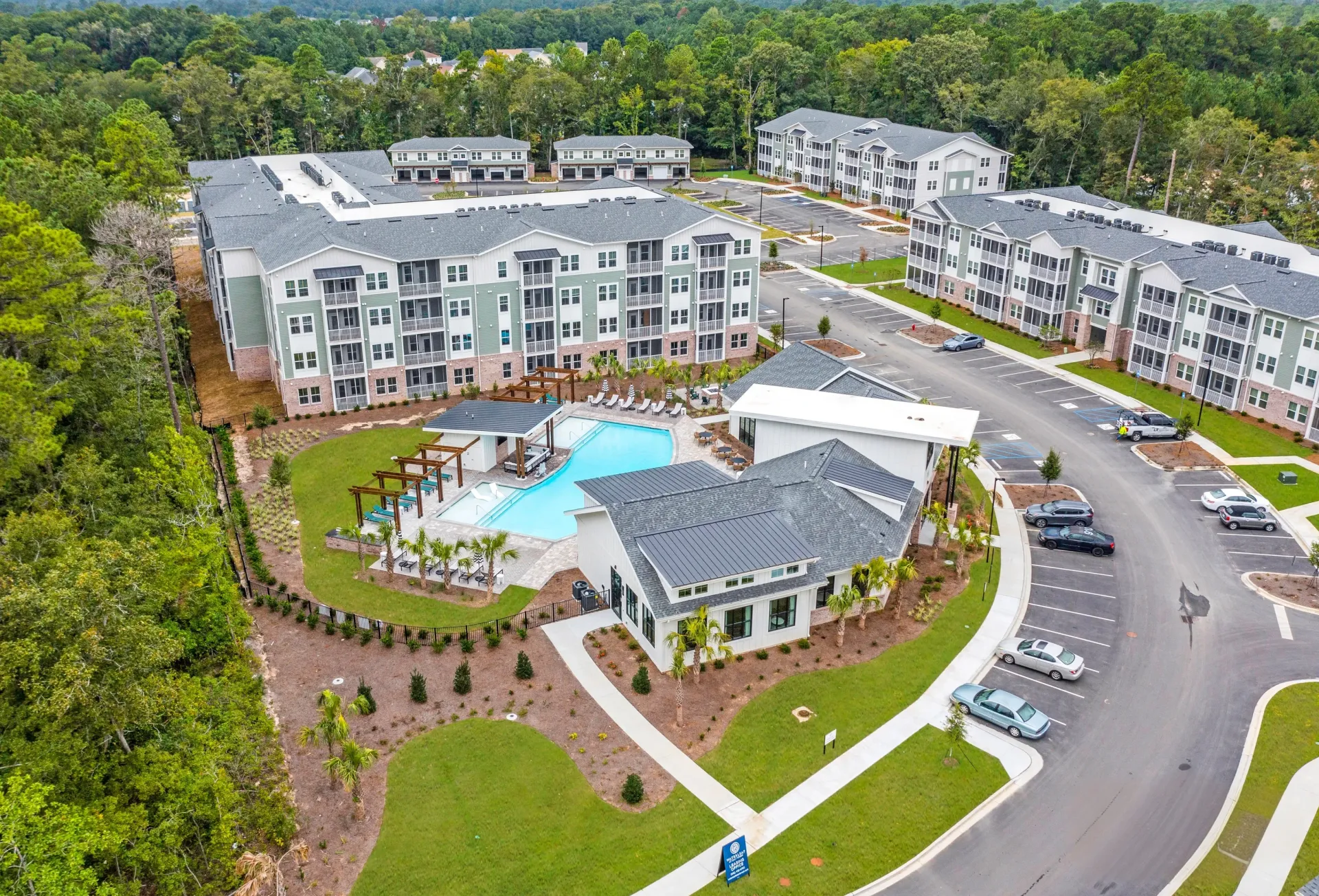 Aerial view of apartment complex with a resort-style pool and modern buildings.