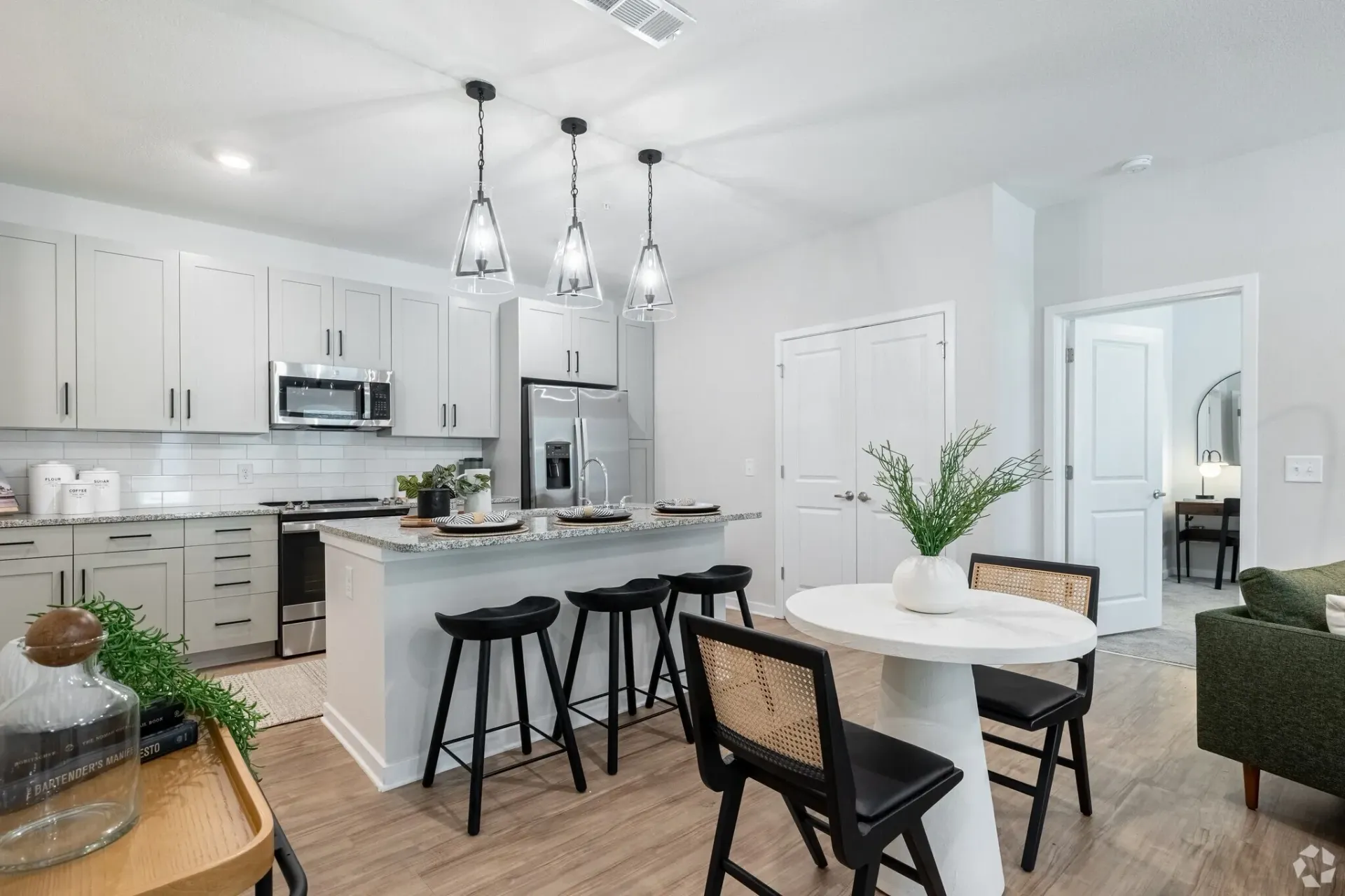 Bright white open-plan kitchen and dining area with island, pendant lights, and dark stools