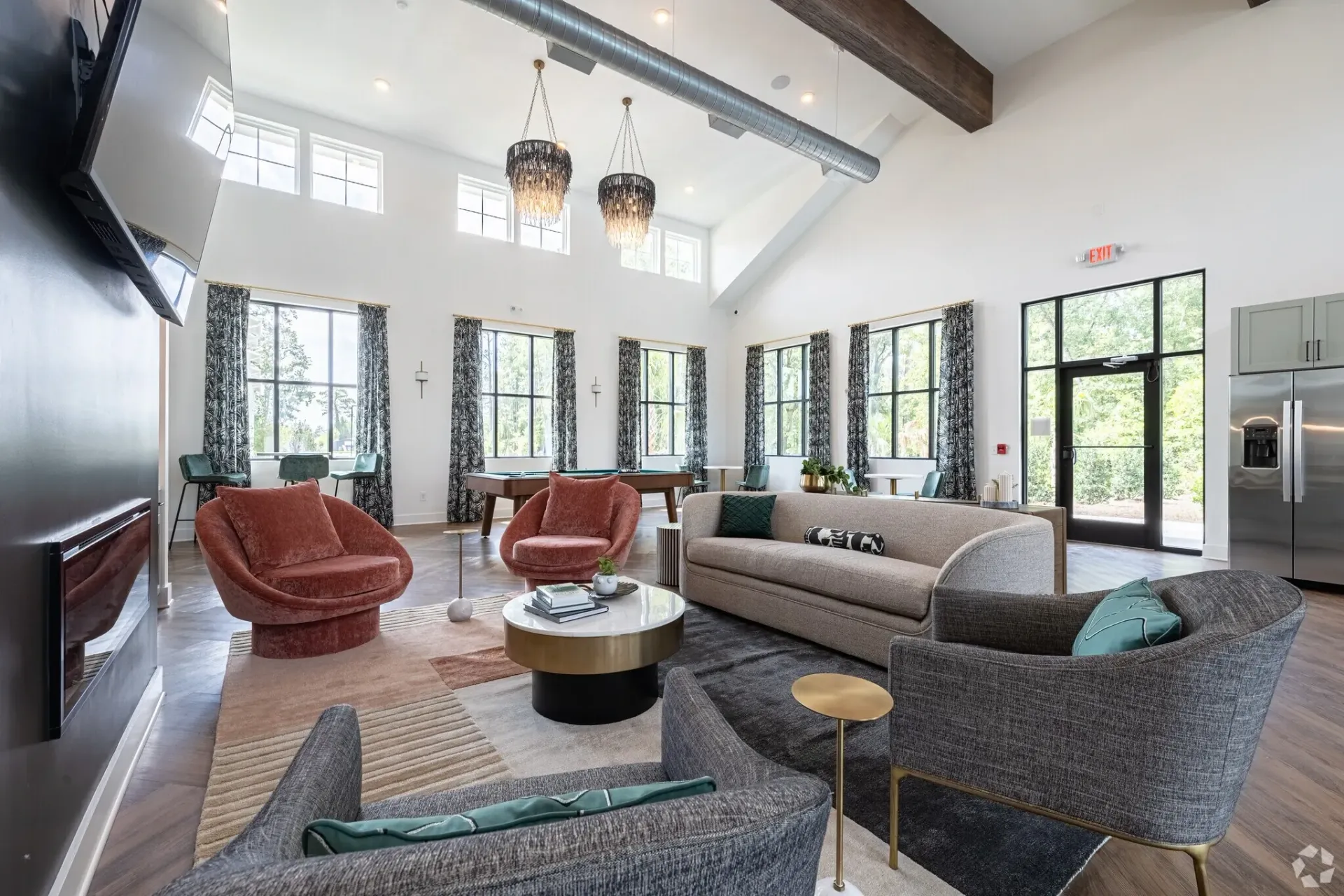 Spacious communal lounge with a pool table, seating area, and large windows.