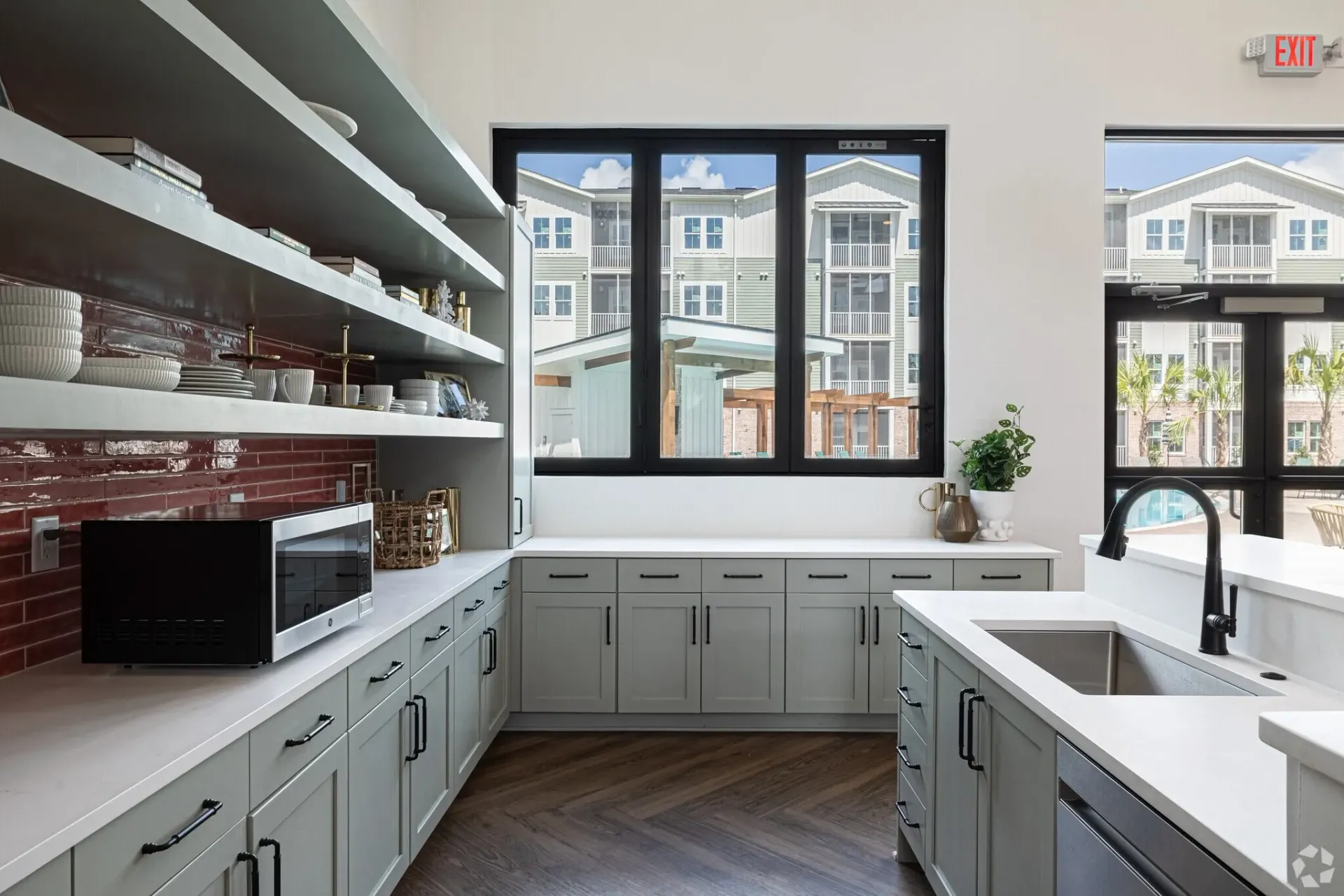Modern communal kitchen with ample storage, microwave, and sink overlooking the property's exterior.
