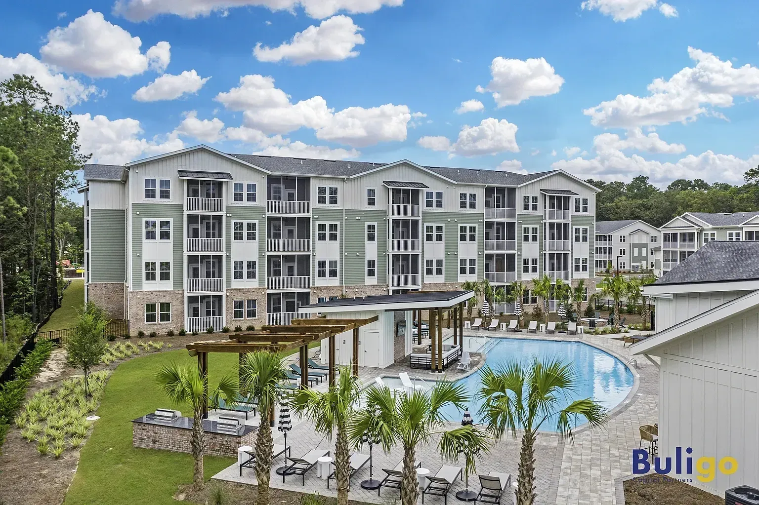 Apartment building exterior with a pool and outdoor seating area.