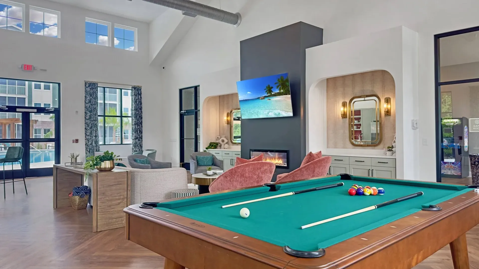 Billiards table and lounge area with pool view in apartment community.