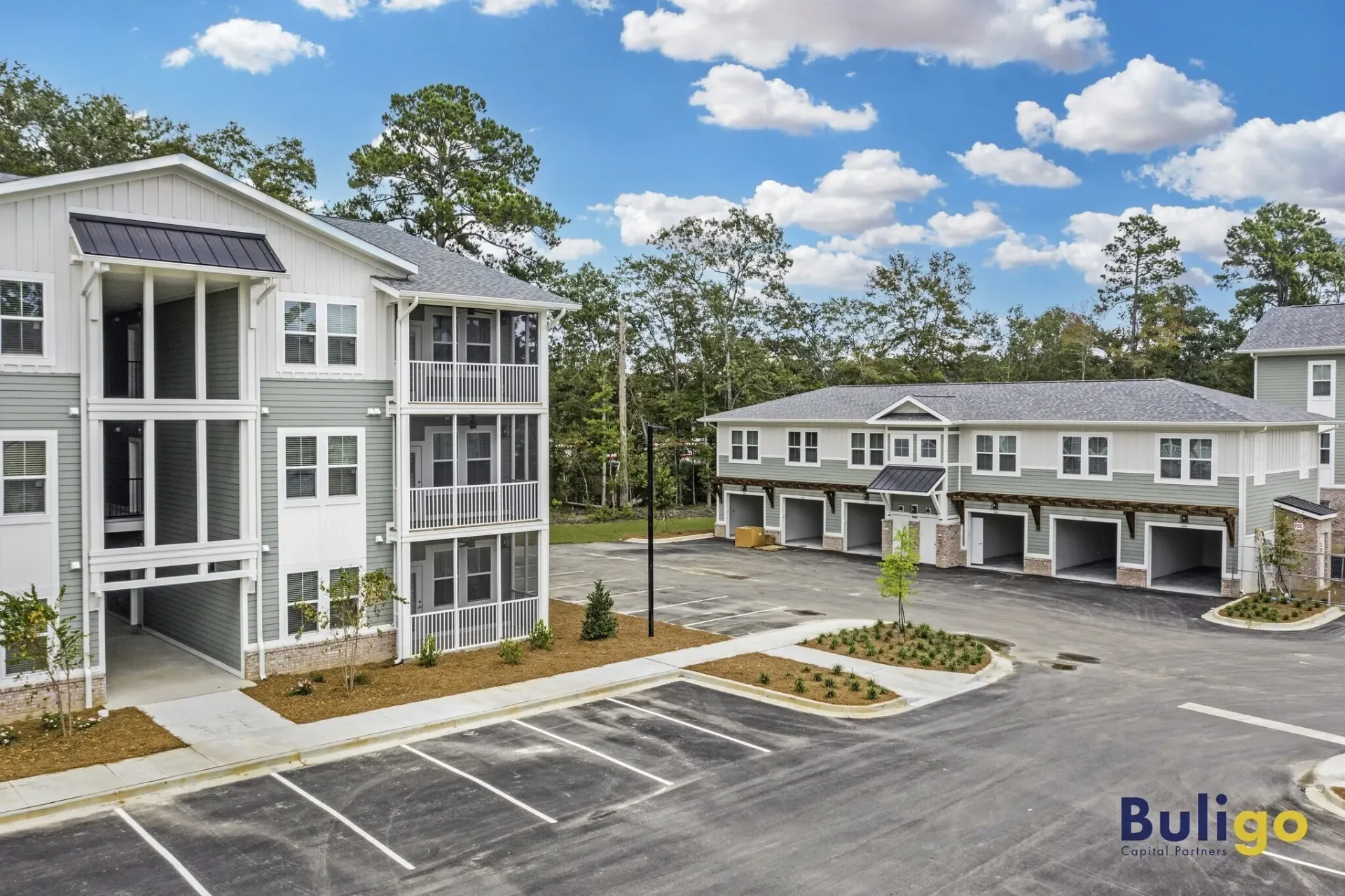 Exterior view of apartment buildings with garages and parking lot.