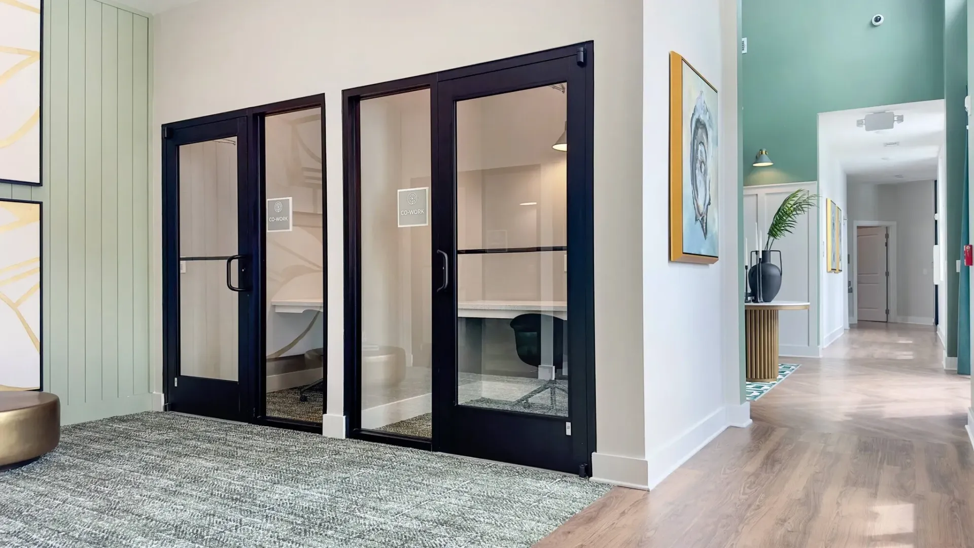 Modern co-working spaces with glass doors and office chairs in apartment building hallway.