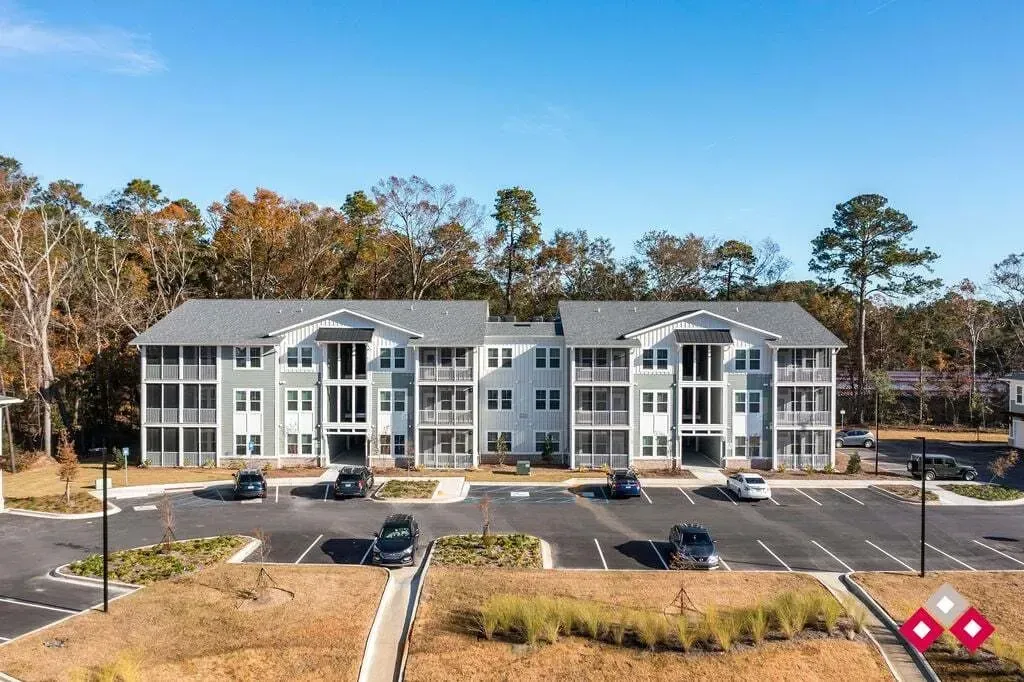 Exterior view of a modern apartment building with multiple stories and balconies, surrounded by trees.