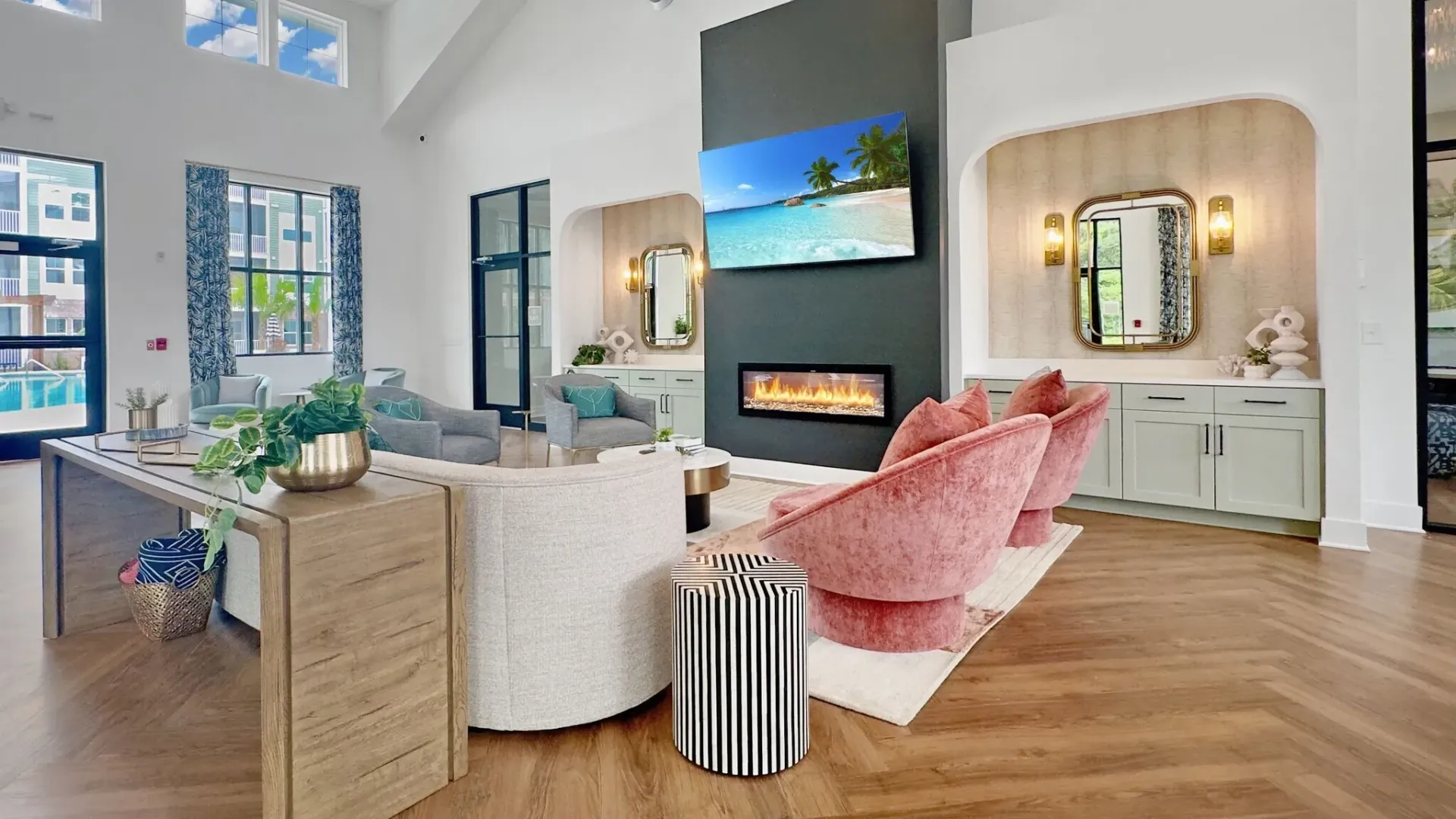 Modern lounge area with fireplace, TV displaying a beach scene, and plush seating.