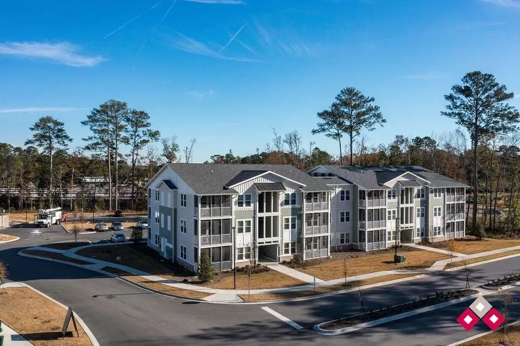 Exterior view of a modern apartment building with balconies and surrounding landscape.