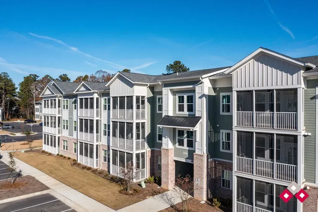 Exterior of a multi-story apartment building with green siding and screened balconies.