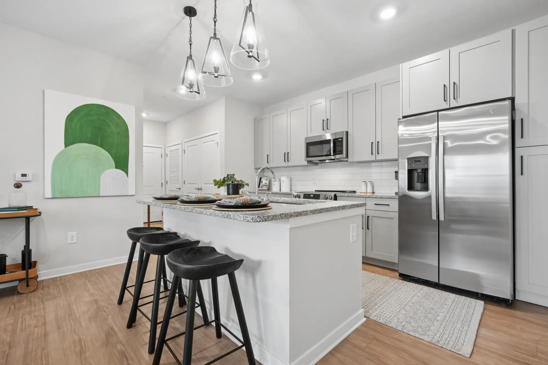 Modern kitchen with stainless steel appliances, granite island, and pendant lights.