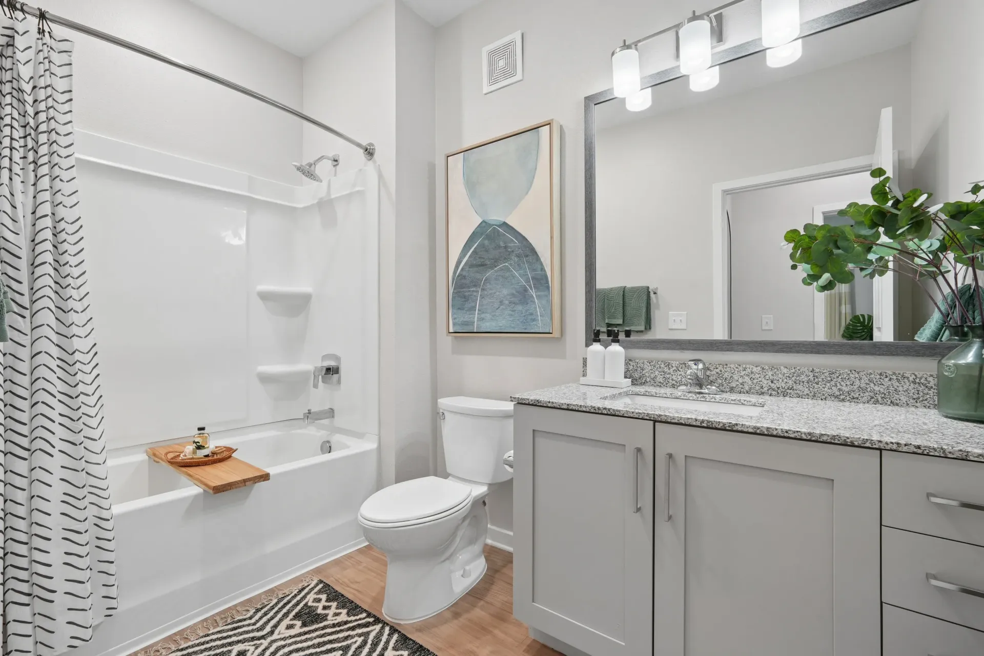 Modern bathroom with a white bathtub, toilet, and vanity.