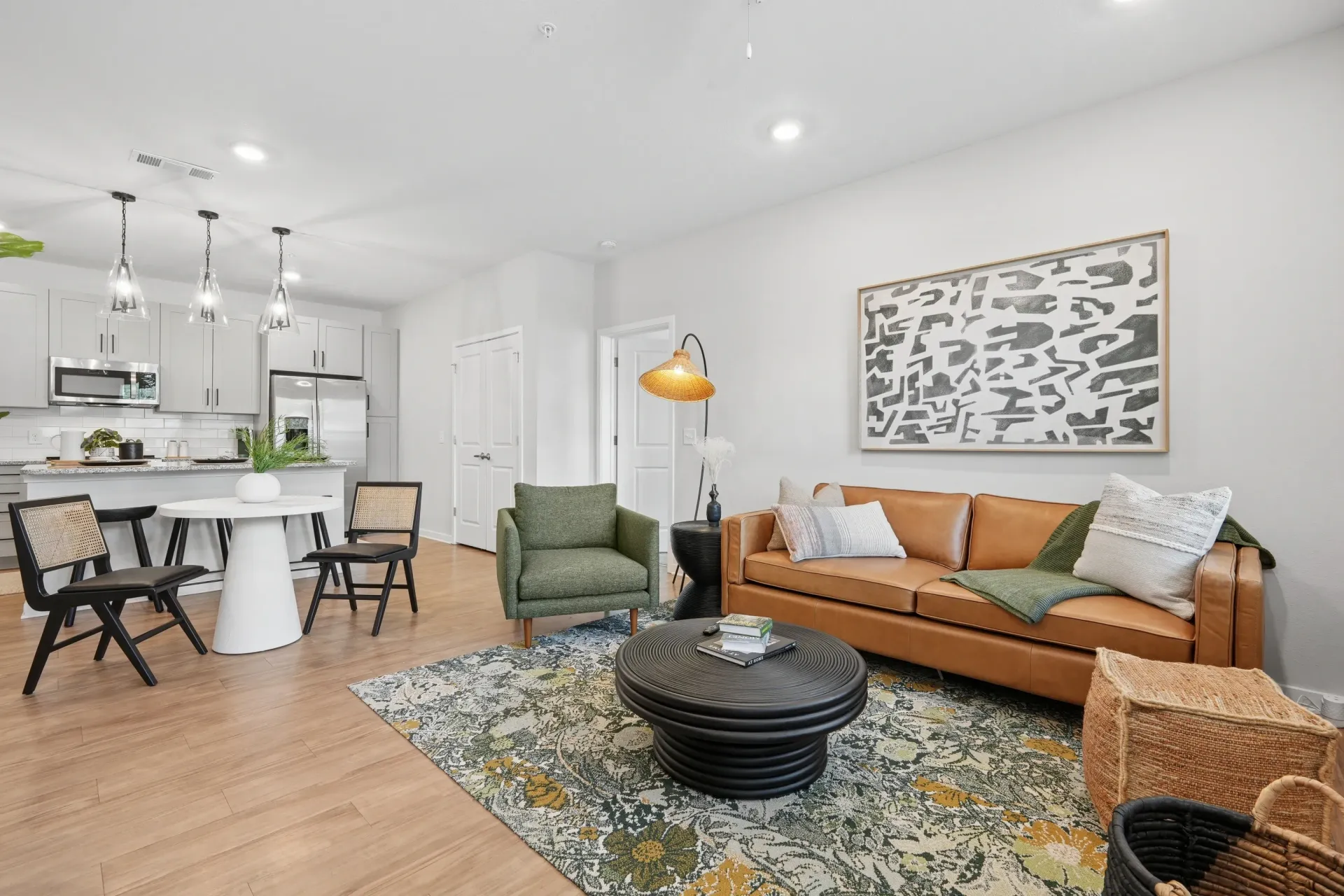 Living room and kitchen area with modern furniture, including a leather sofa and dining table.