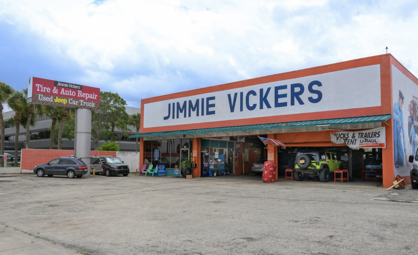 Jimmie Vickers store frontage with orange trim, large sign, cars parked outside, and a cloudy sky