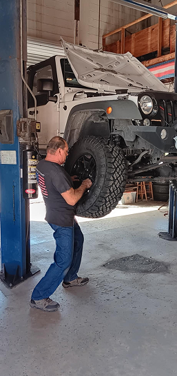 Mechanic working on a lifted off-road vehicle in an auto repair shop