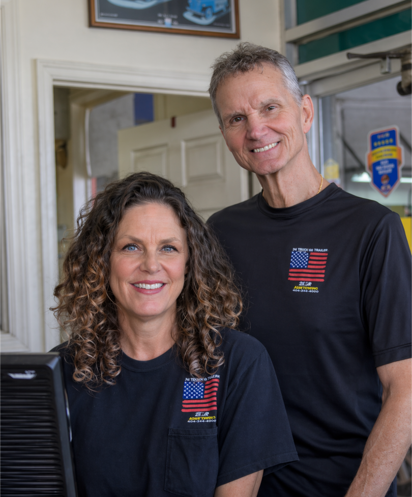 Two smiling people in matching black T-shirts standing indoors near a doorway.