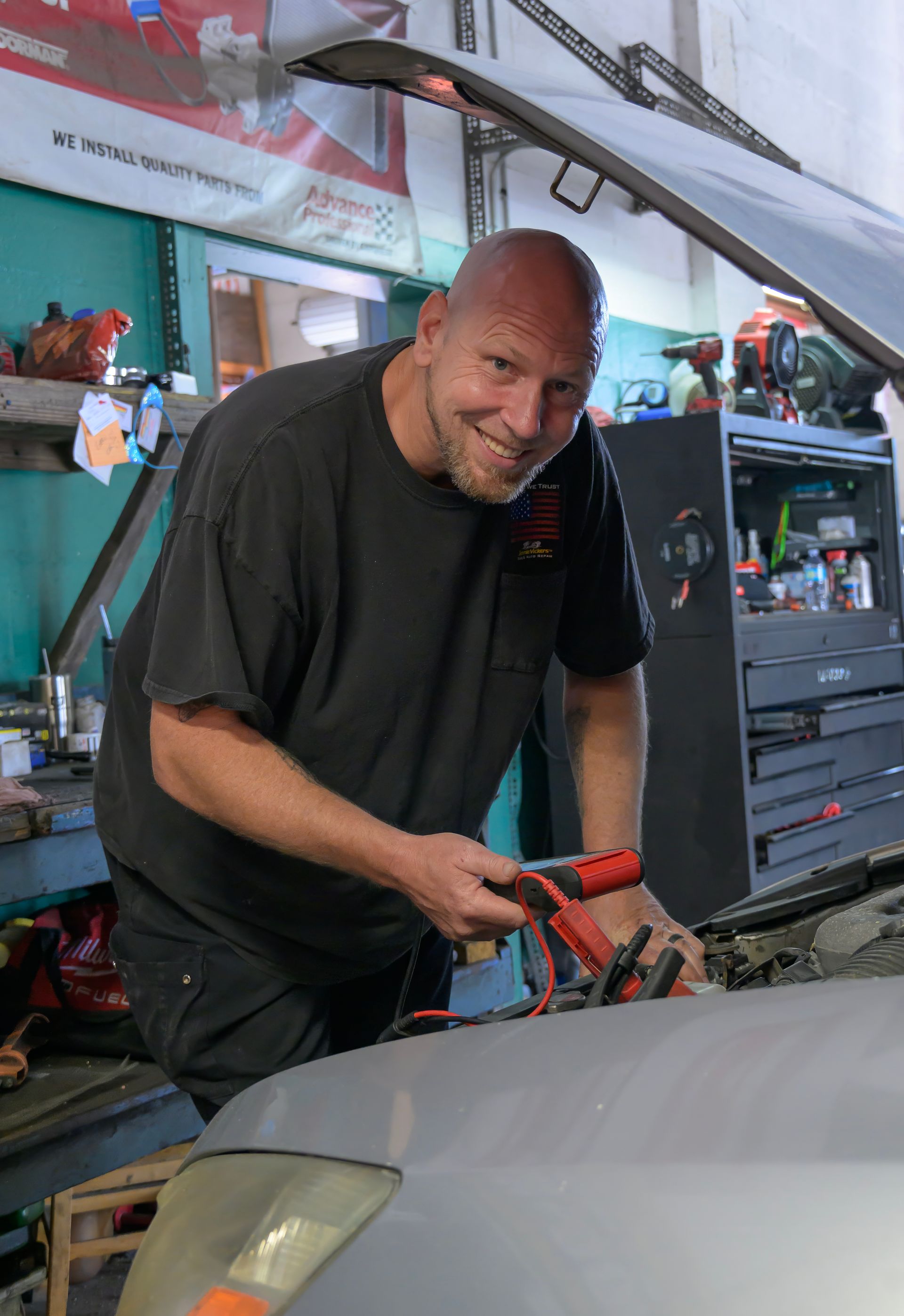Mechanic using a red tool on a car in a repair shop