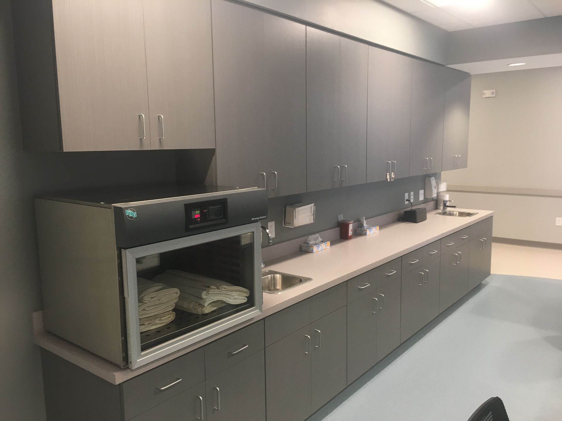 A gray laboratory cabinet with upper and lower storage, and an incubator with a glass door.