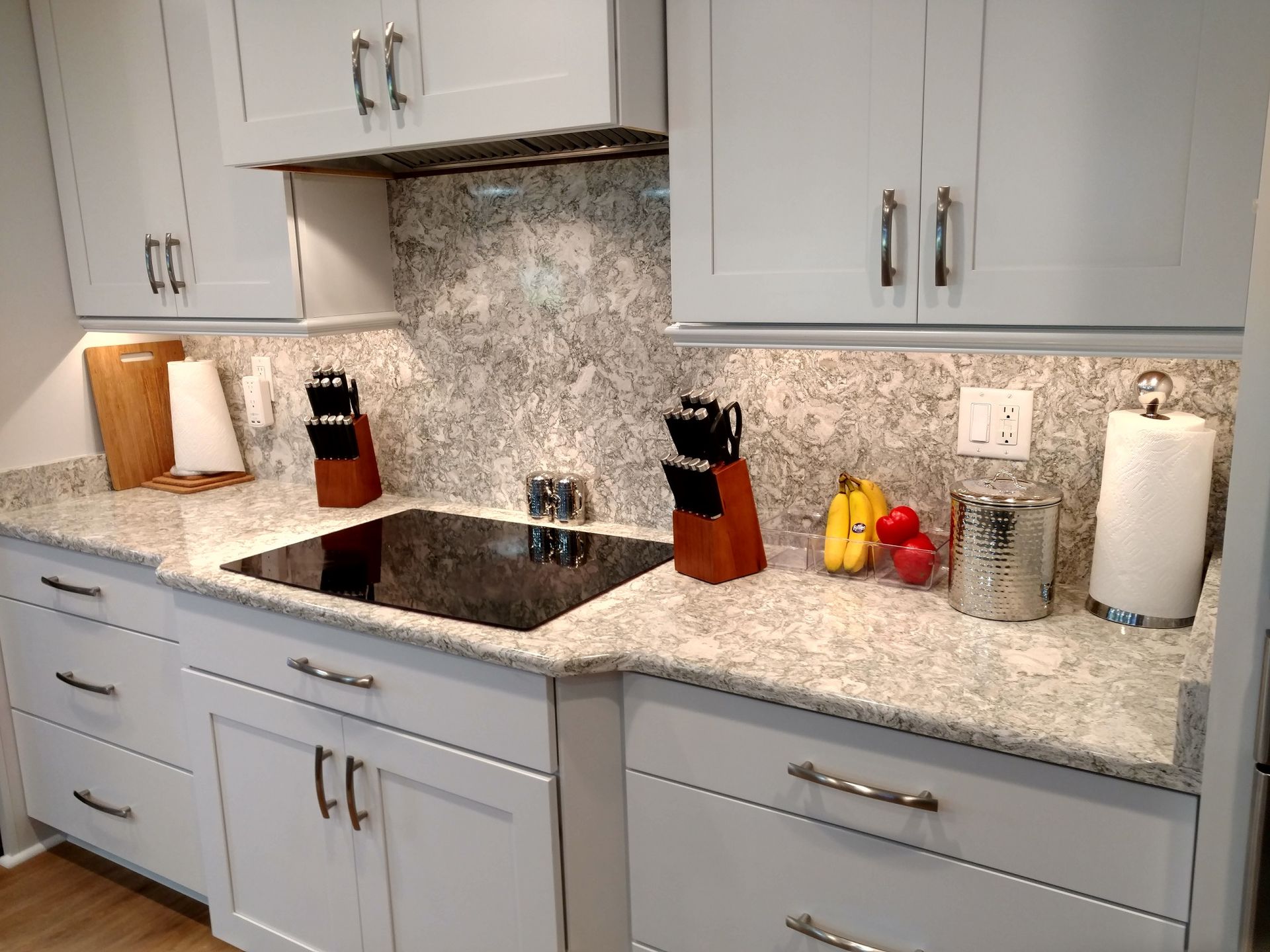 Light gray kitchen with white countertops, light gray cabinets, and stainless steel appliances.