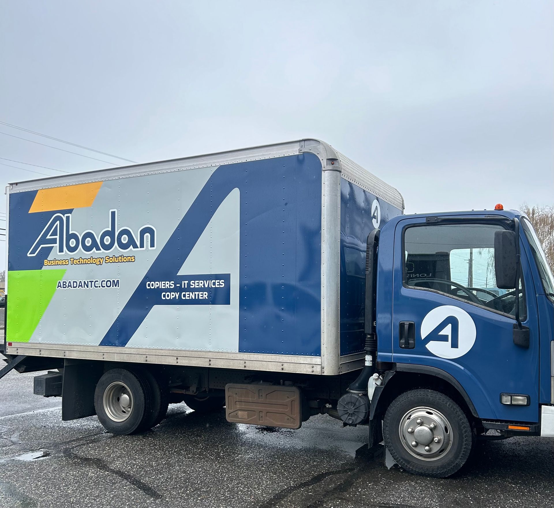 Blue Abadan box truck, parked outdoors on a cloudy day.