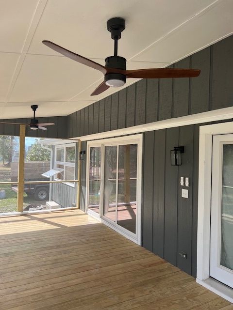 Covered porch with gray siding, white trim, wooden deck, and ceiling fans.