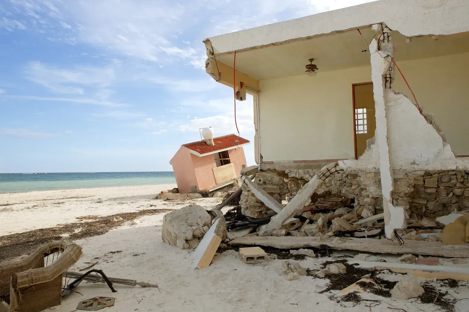 Beachfront building destroyed by natural disaster, showing structural damage.