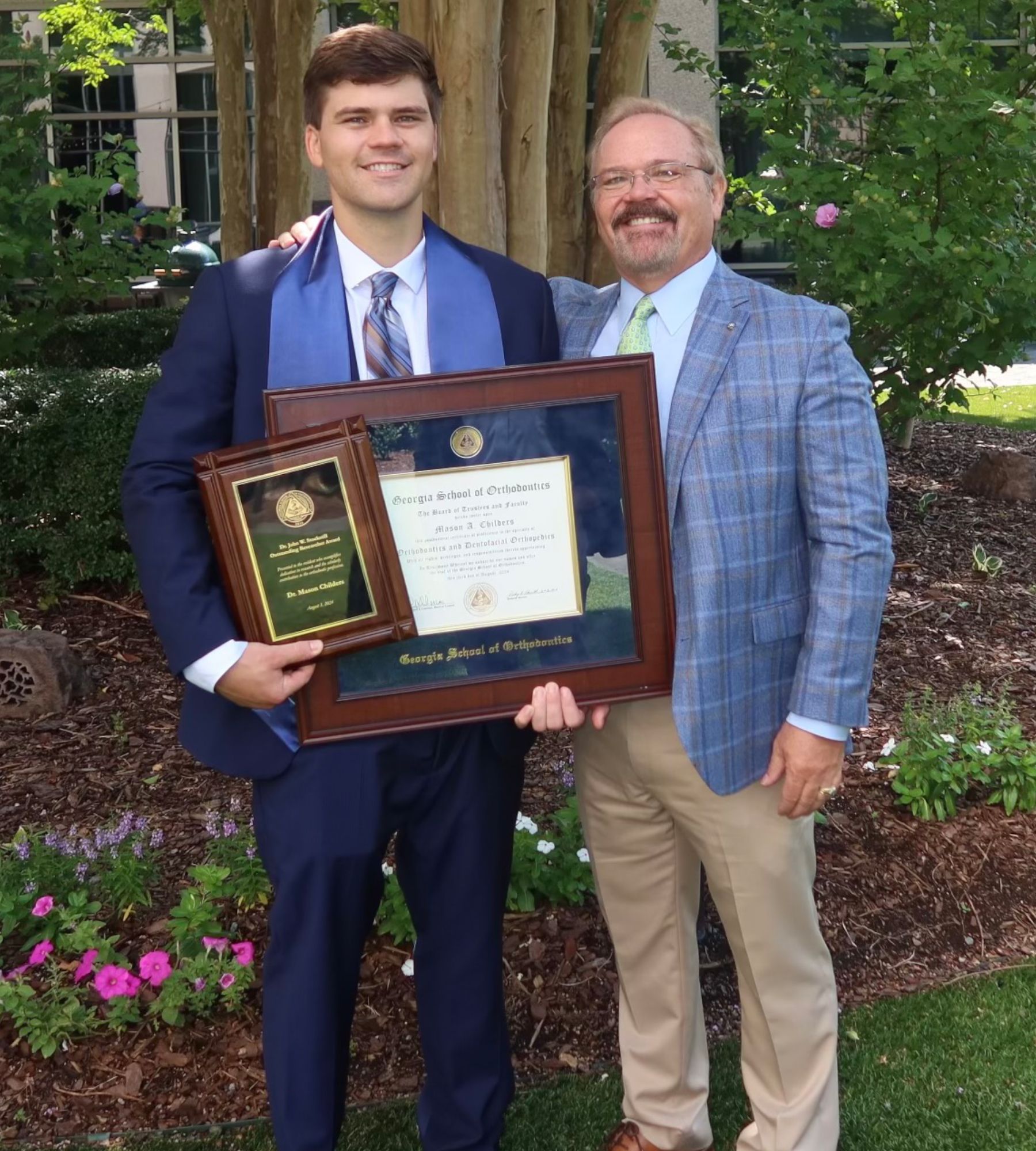 Two men standing next to each other holding framed plaques