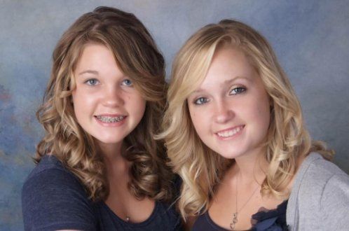 Two girls are posing for a picture and one has braces on her teeth