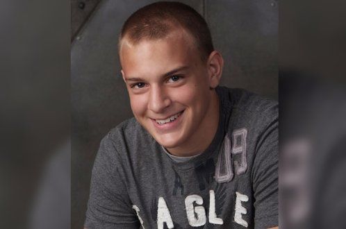 A young man wearing an eagle shirt is smiling for the camera.