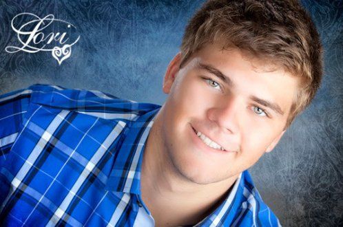 A young man in a blue plaid shirt is smiling for the camera.