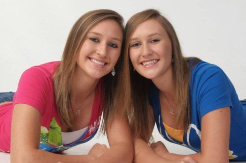Two girls are laying on the floor and smiling for the camera