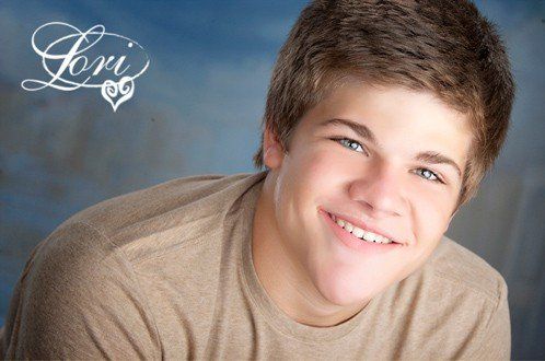 A young boy is smiling in front of a blue background with the name lori on it
