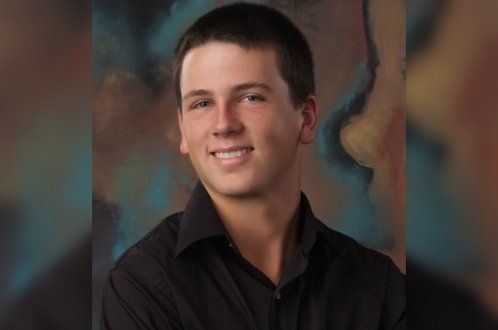 A young man in a black shirt is smiling for the camera.