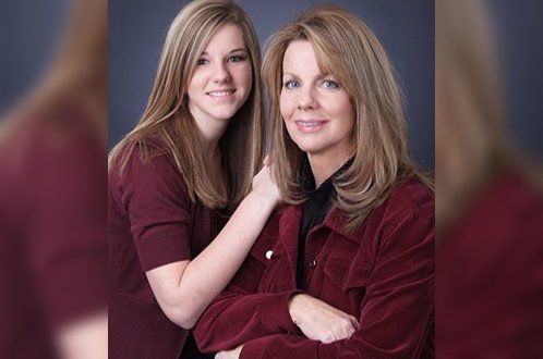 A mother and daughter are posing for a picture together.