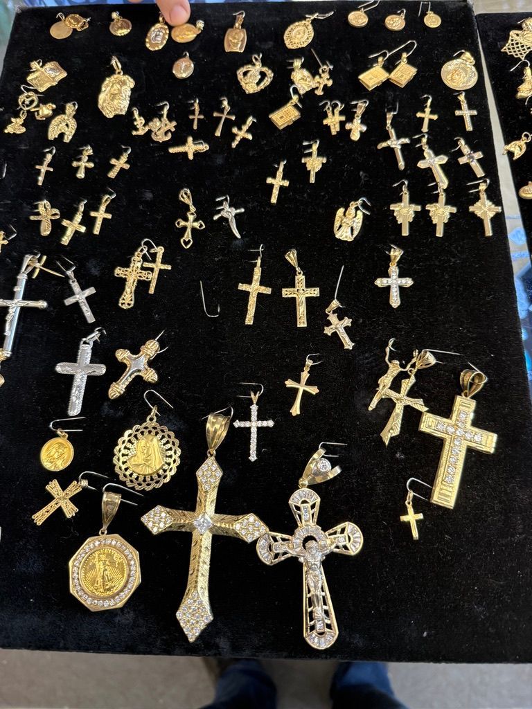 Assorted gold and silver cross pendants displayed on black velvet