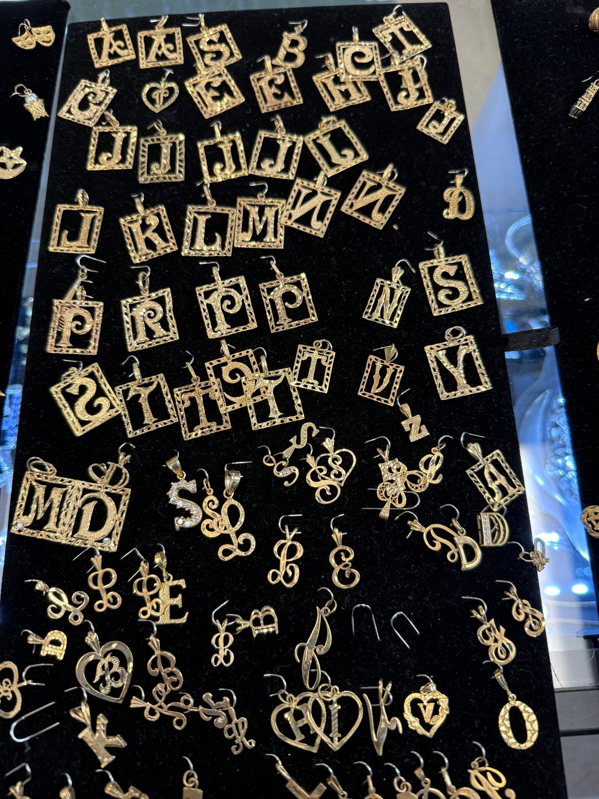 Black display board covered with many small gold earrings in assorted geometric designs