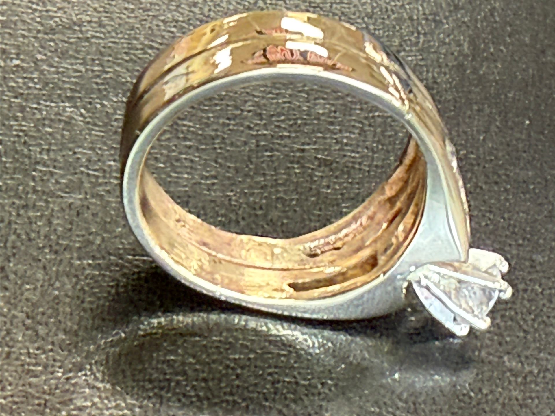 Gold ring with a clear gemstone set on a dark textured surface