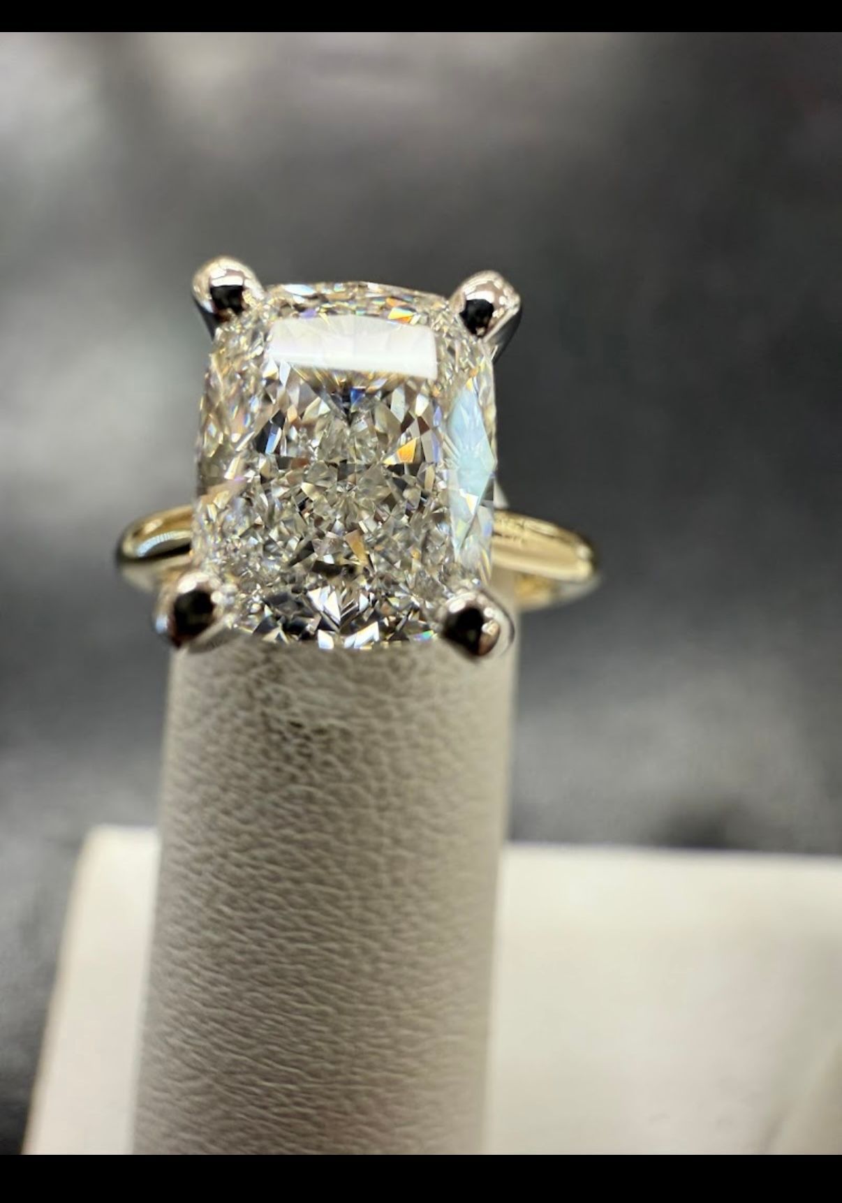 Oval diamond engagement ring with gold band on a display stand