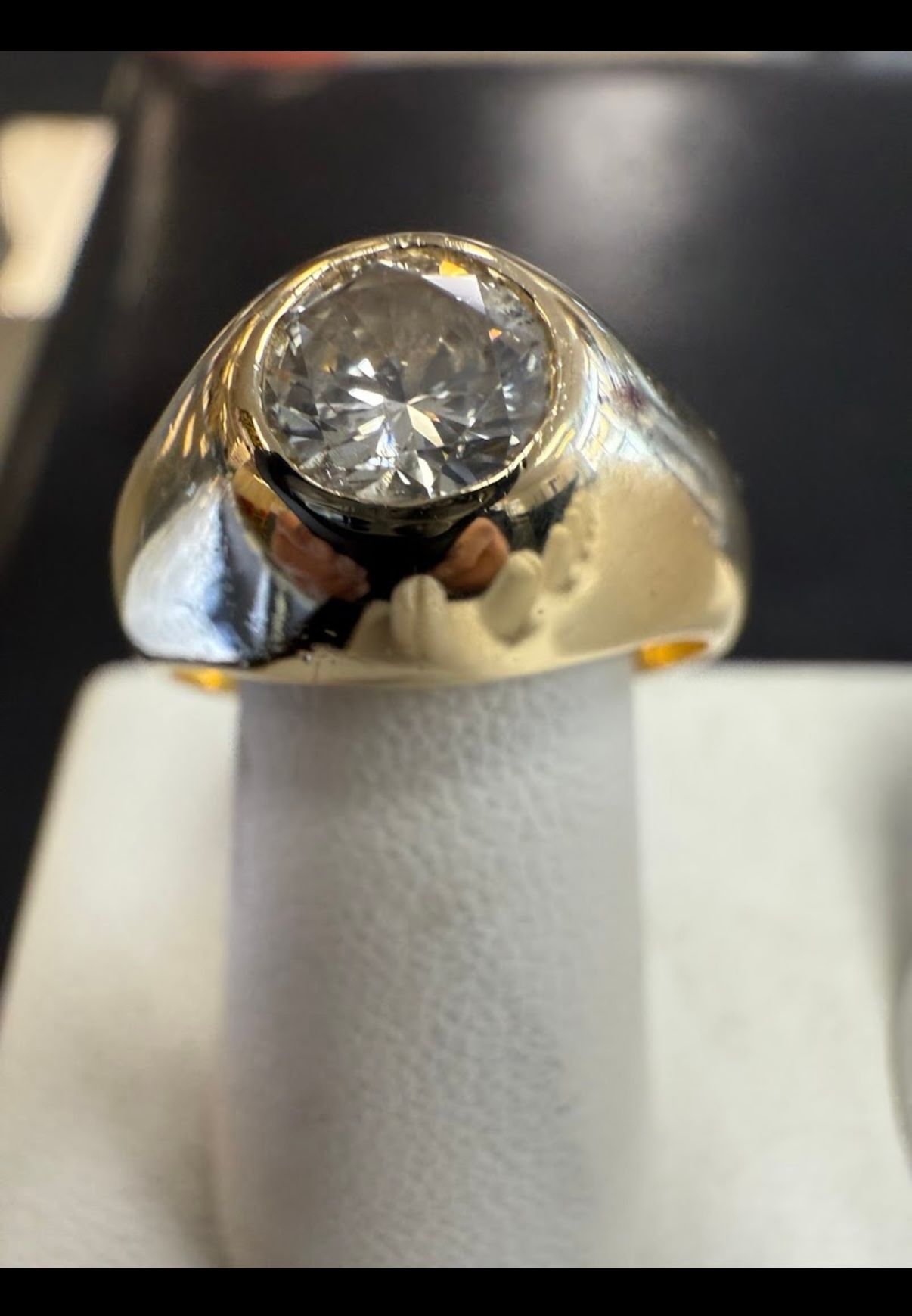 Close-up of a gold ring with a large clear gemstone on a white display stand