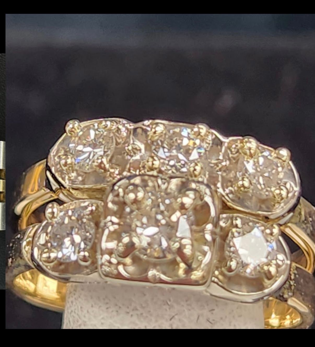 Gold ring with five large clear gemstones on a dark background