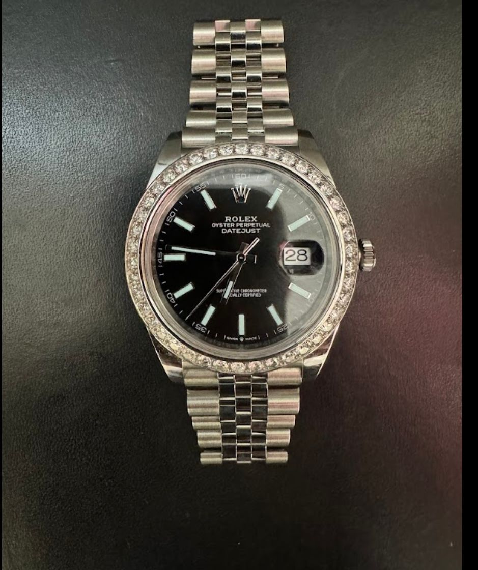 Silver wristwatch with black dial and date display on a dark background